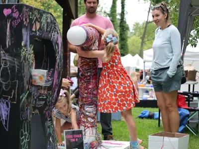 young girl hugging "ART" sign