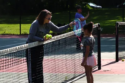 coach and kid about to high-five with a tennis racket